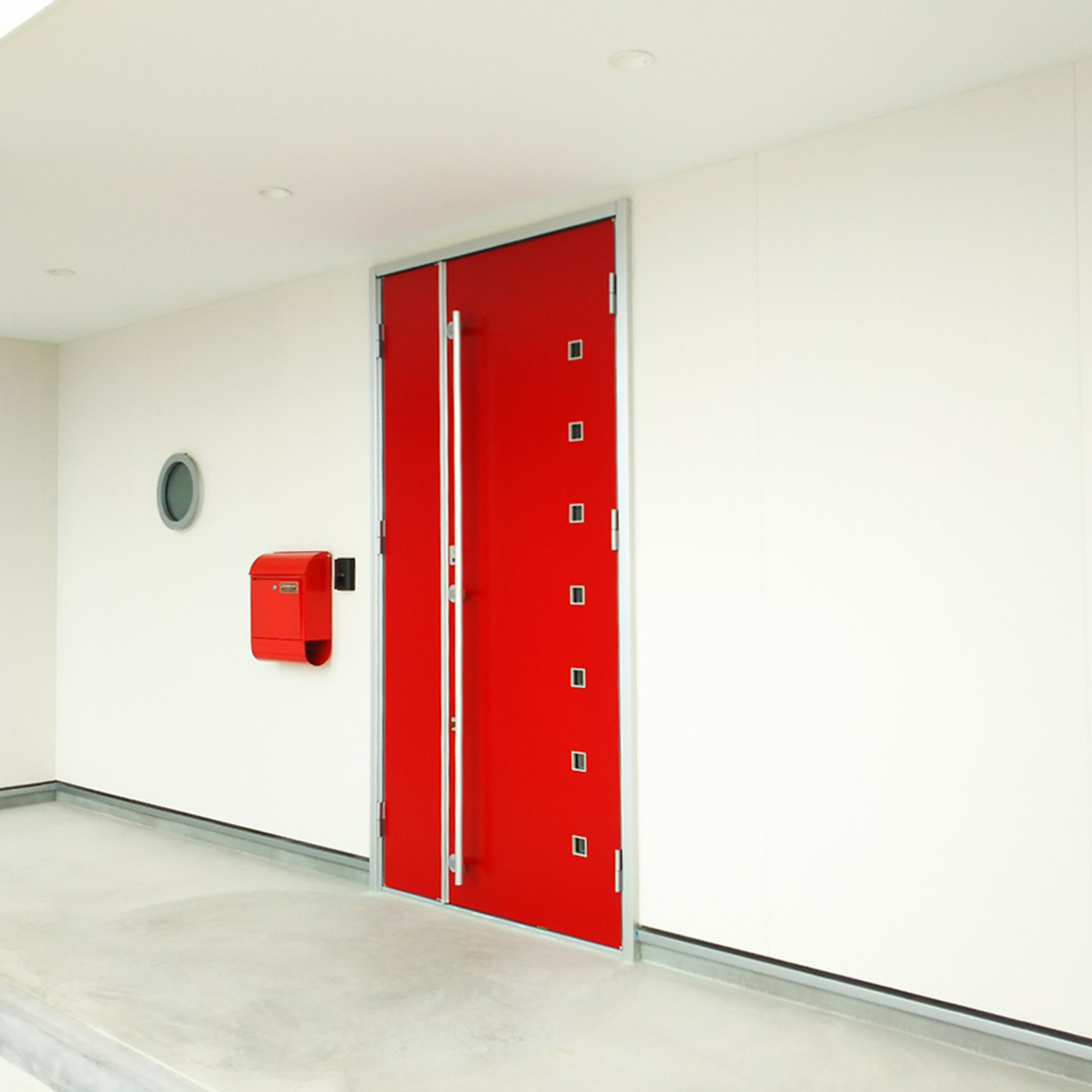 真っ白な外壁と赤い玄関ドアが印象的な家