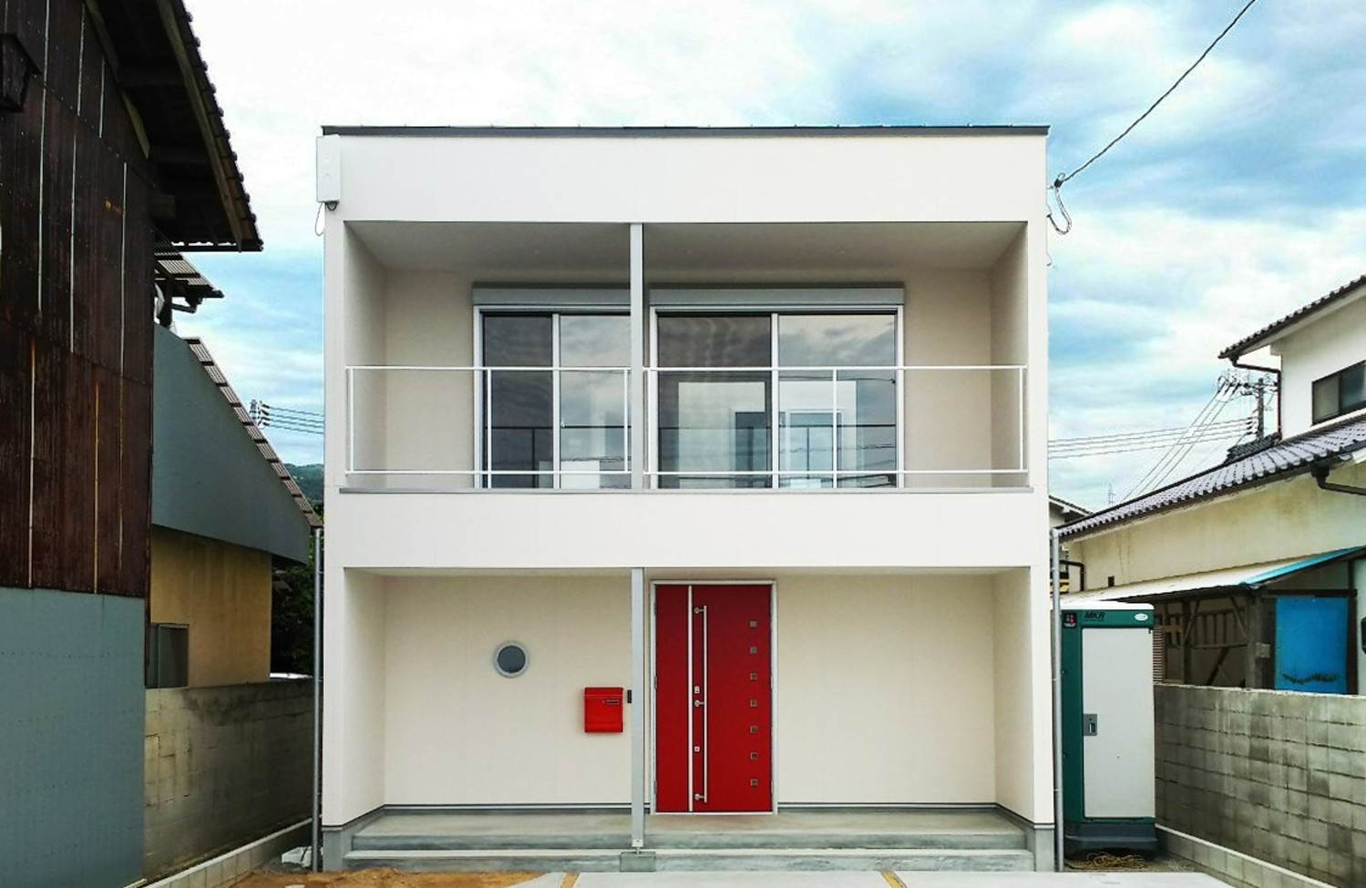 真っ白な外壁と赤い玄関ドアが印象的な家